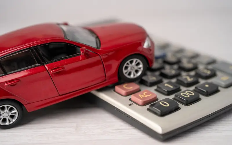 Red toy car sitting on top of a calculator