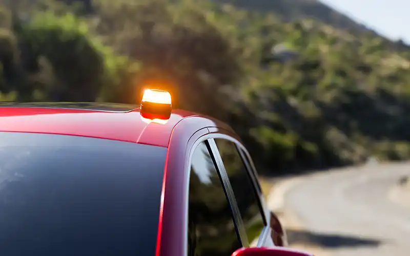flashing v16 beacon on top of red car