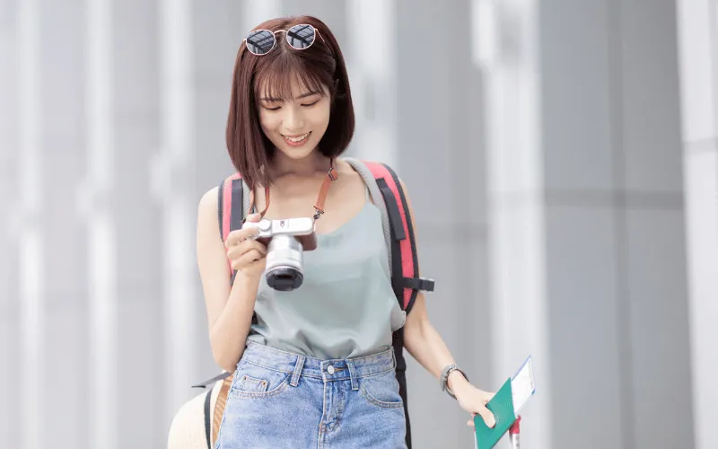 Asian tourist at airport holding camera and passport