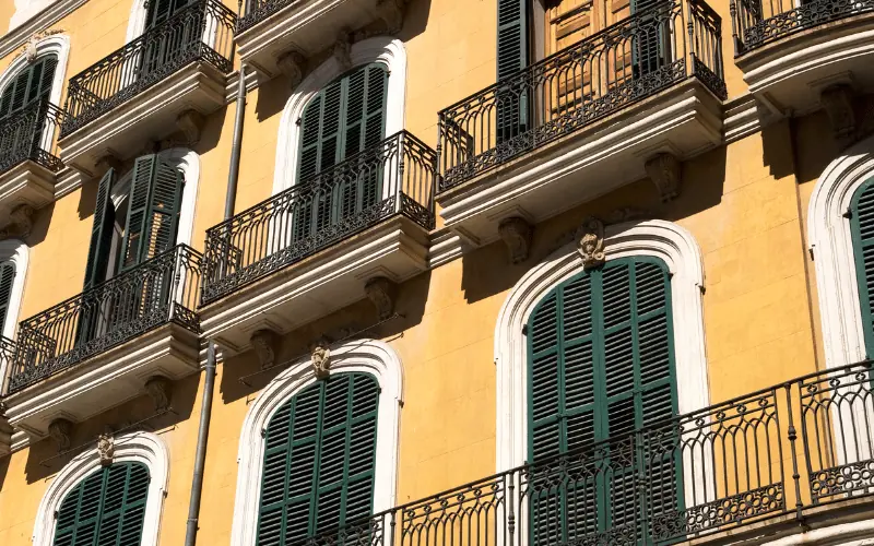 Traditional Balearic apartment balconies with green shutters on a sunny day