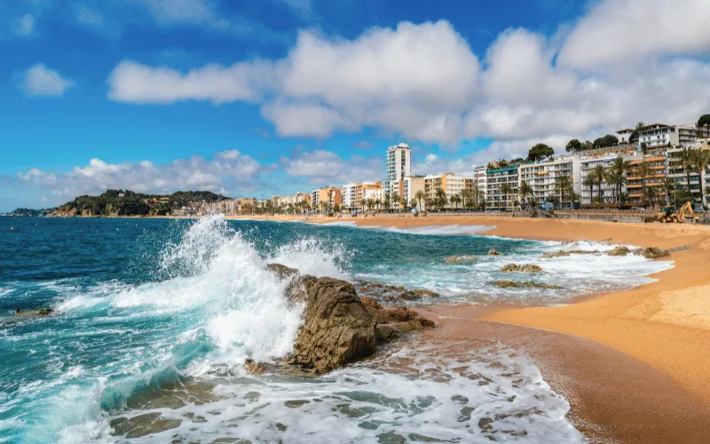 Waves crashing on a beach in Barcelona with city buildings in the background