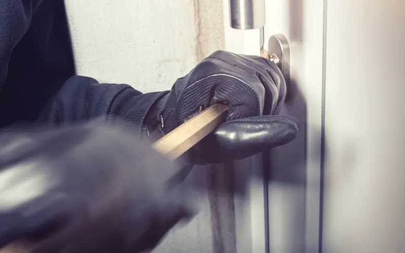 Person attempting home break-in using a crowbar, highlighting burglary risks in Spain