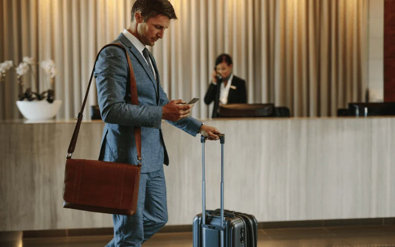 Business traveler checking into a hotel with suitcase and mobile phone