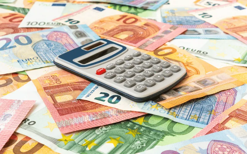 Calculator on top of scattered euro banknotes representing financial planning in Europe