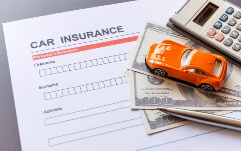 Car insurance application form with toy car, money and calculator on desk