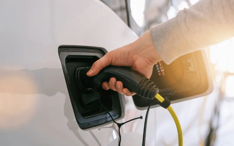 Person charging an electric vehicle at a charging station in Spain