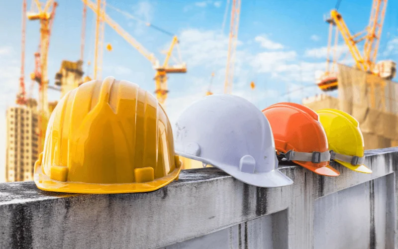 Safety helmets on construction site wall under cranes and blue sky