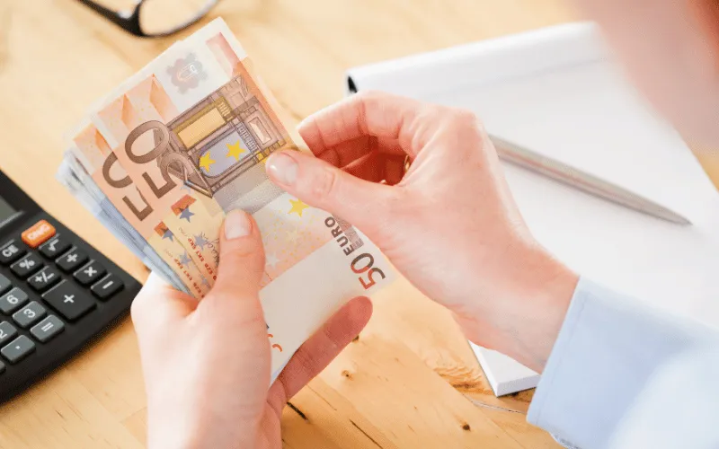 Person counting 50 euro banknotes at desk for budgeting in Spain