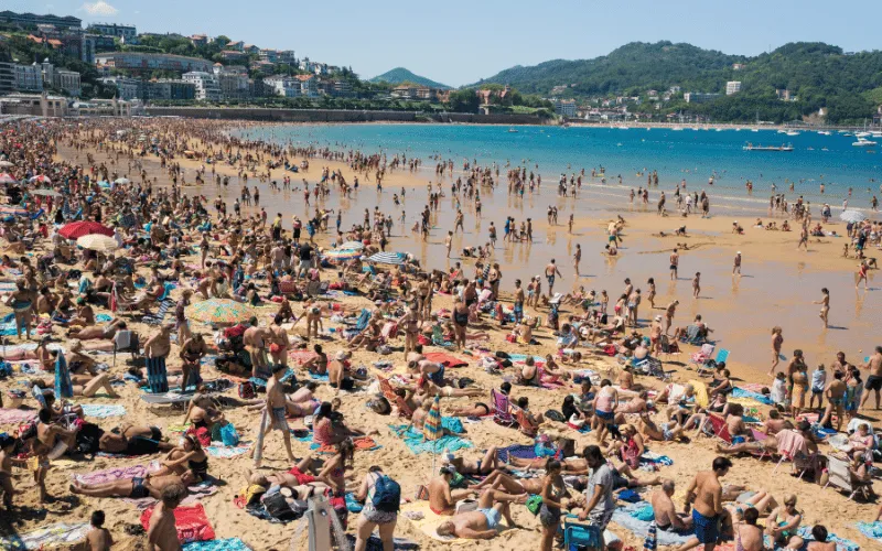 Tourists sunbathing on a crowded beach in Spain during summer holiday season