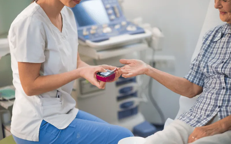 Nurse checking blood sugar levels of elderly woman in clinic