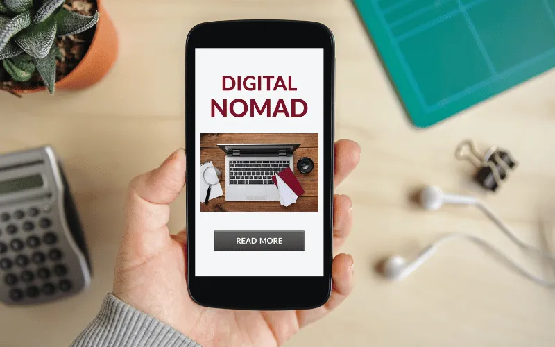 Person holding phone with digital nomad article and travel essentials on screen