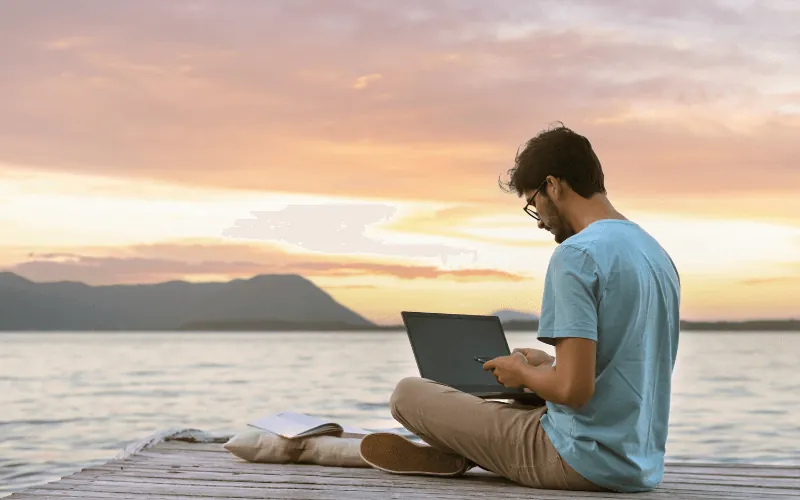 Remote worker using laptop by the sea during sunset in Spain