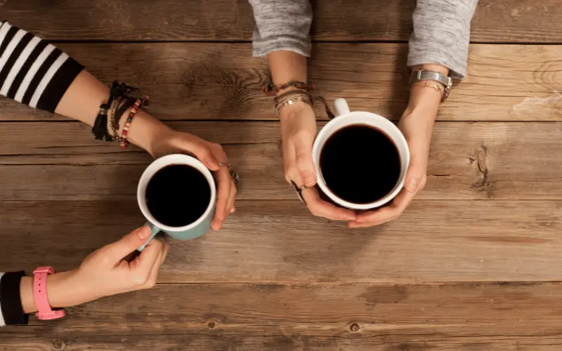 Friends sitting at a wooden table enjoying coffee together