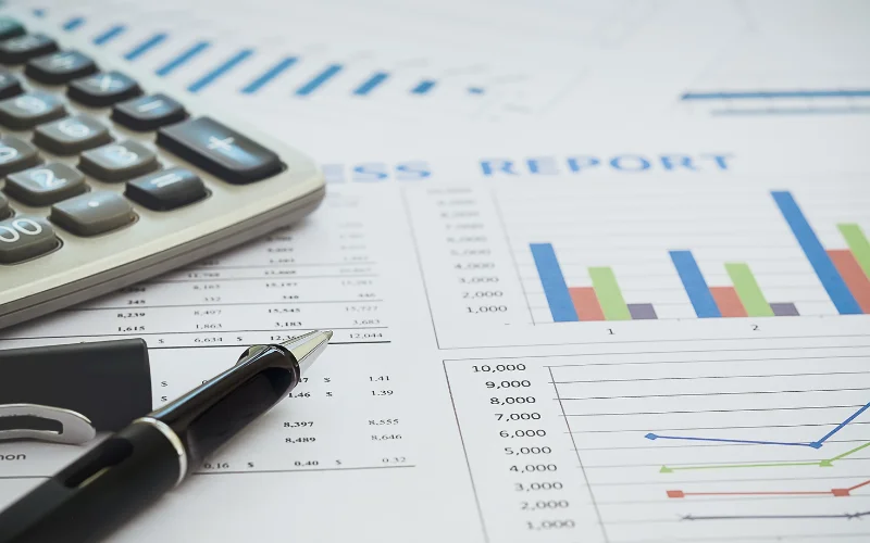 Pen and calculator on financial report showing economic growth charts and data analysis