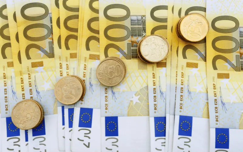 Stacks of euro coins on top of multiple 200 euro banknotes symbolizing economic growth