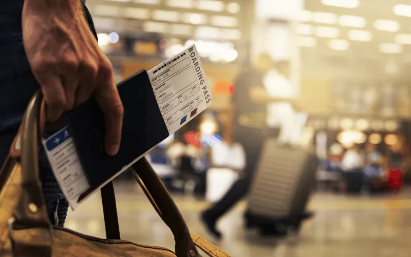 Traveler holding passport and boarding pass at airport departure terminal