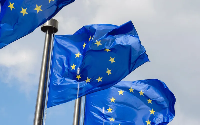 European Union flags waving against a cloudy sky outside EU headquarters
