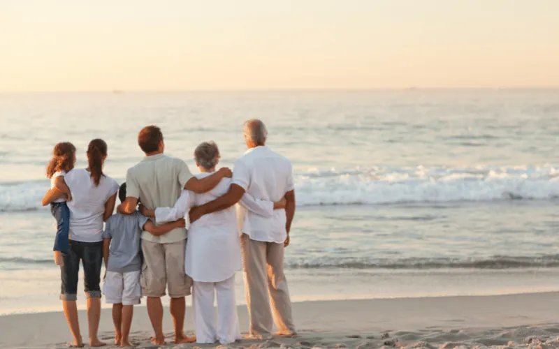 Three generations of family enjoying a peaceful beach sunset together