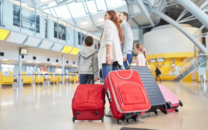 Family with luggage at airport check-in counter ready for holiday travel