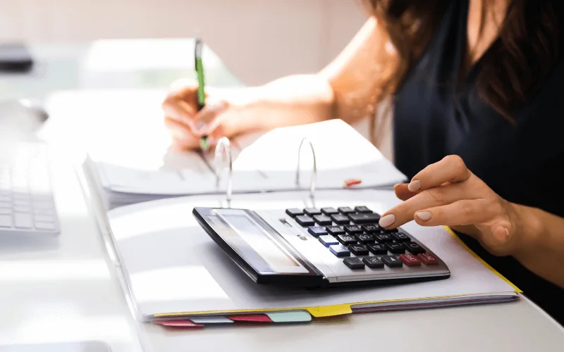 Person calculating finances and filling out tax documents at desk