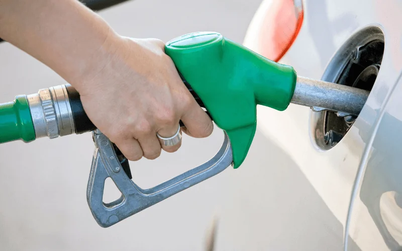 Close-up of hand refueling car at gas station with green fuel nozzle