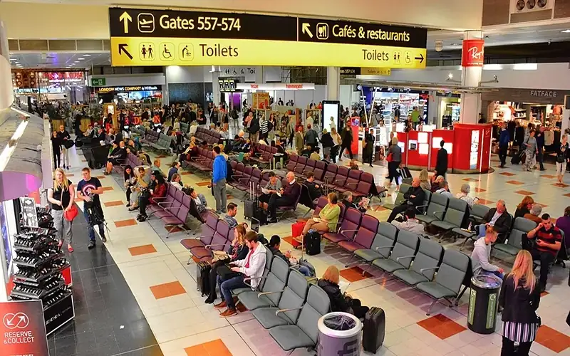 Busy departure lounge at Gatwick Airport North Terminal with travelers and shops