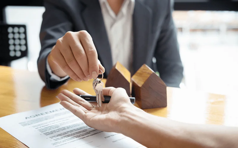 Real estate agent handing house keys to new property owner after signing agreement