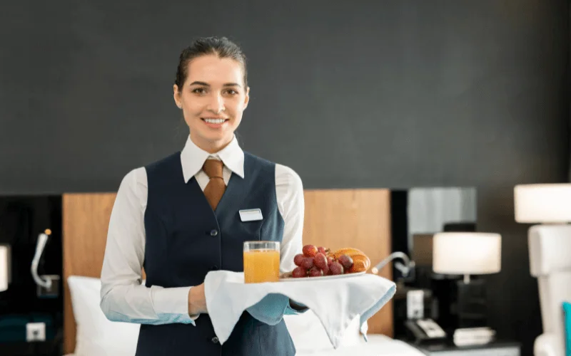 Hotel staff member delivering breakfast to guest room with a smile