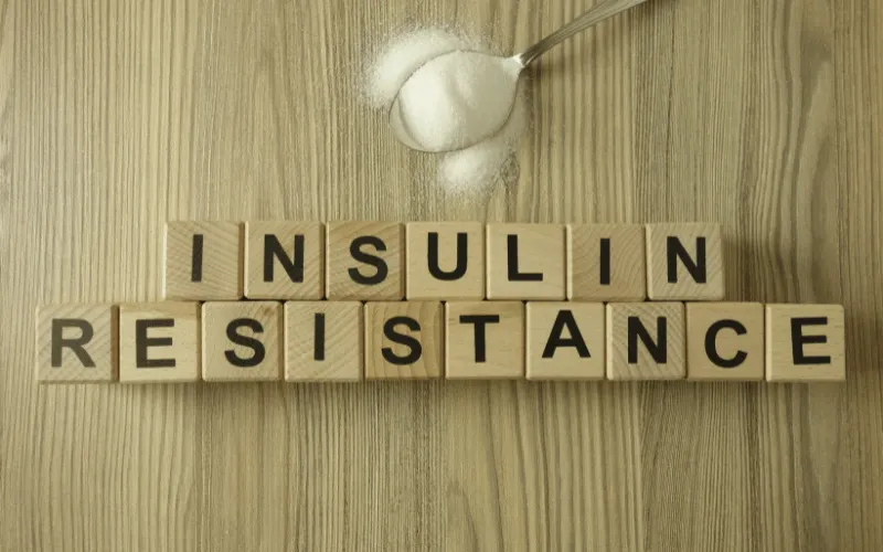 Wooden blocks spelling insulin resistance with spoonful of sugar on wooden table