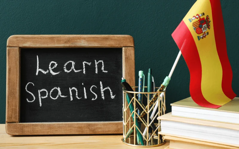 Learn Spanish concept with chalkboard, books and Spain flag on desk