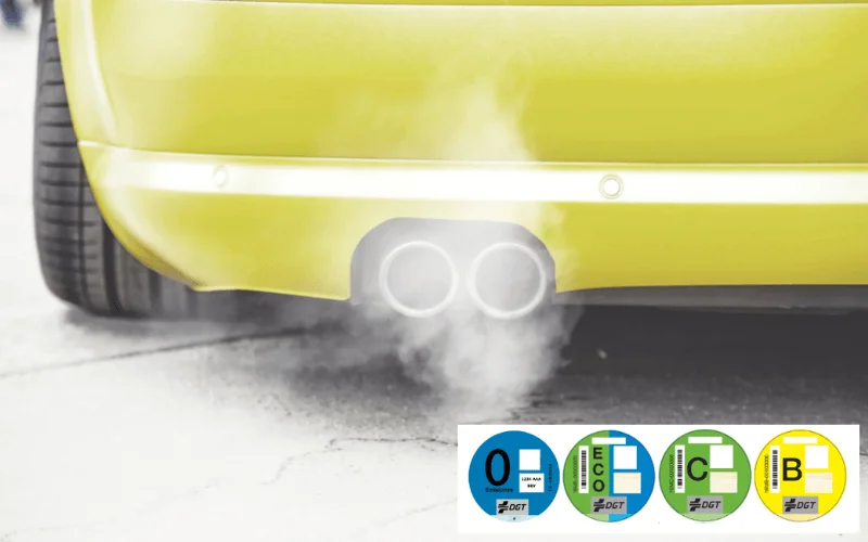 Car emitting exhaust fumes with DGT environmental labels for low emission zones in Spain