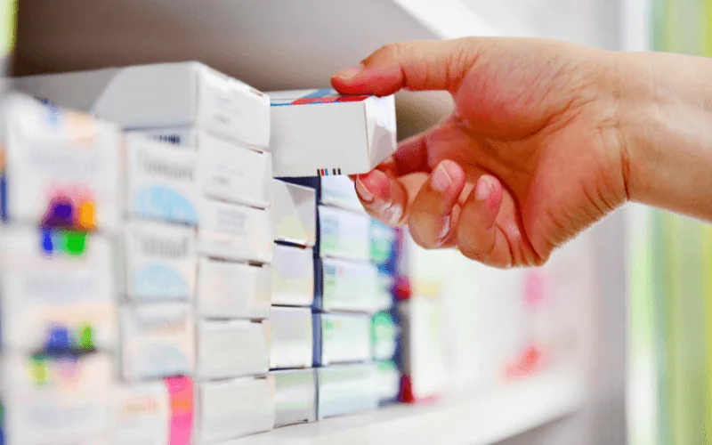 Customer picking up medicine box at pharmacy shelf