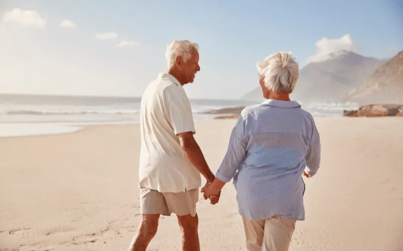 Senior couple walking hand in hand on a peaceful beach during sunset