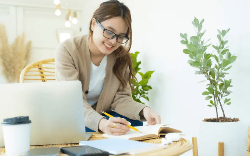 Student studying with laptop and notes in a cozy, well-lit home workspace
