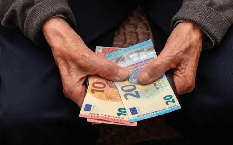 Senior counting euro banknotes, illustrating pension income in Spain