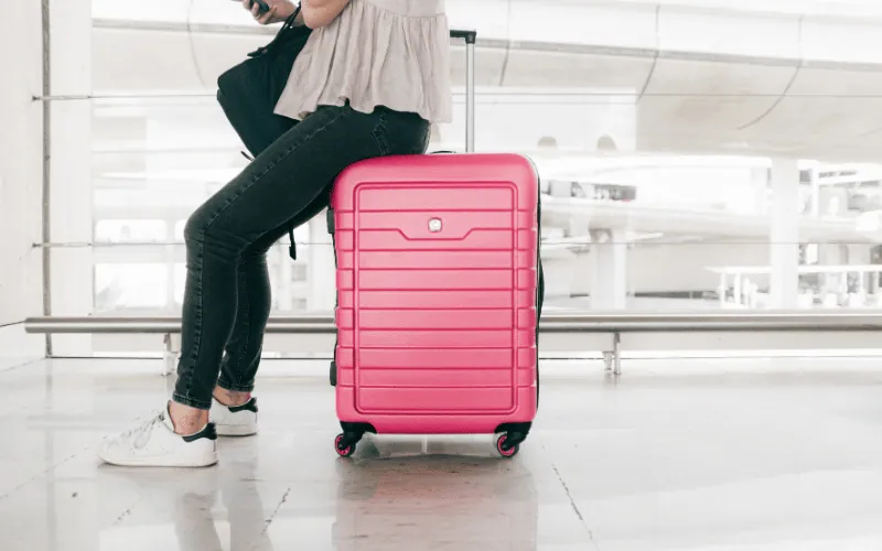Passenger sitting with pink suitcase at airport terminal