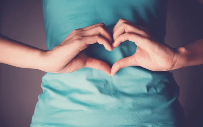 Hands forming heart shape on stomach to represent gut health and probiotics benefits