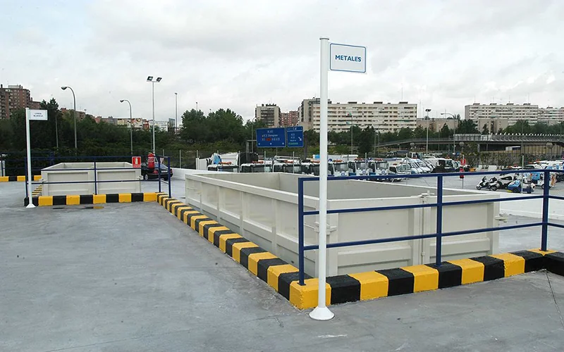 Recycling facility in Madrid with metal disposal container and city background