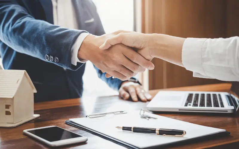 Real estate agent and client shaking hands after signing property agreement