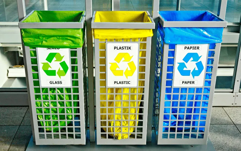 Recycling bins for glass, plastic and paper with color-coded bags in a public area