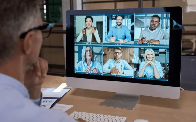Man attending virtual team meeting with remote colleagues on computer screen