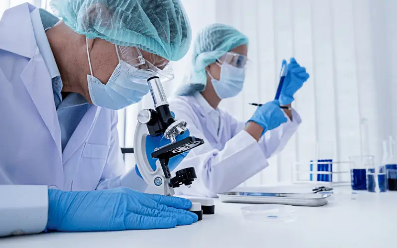 Scientists working in a laboratory using a microscope and test tubes during medical research