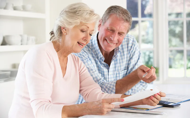 Happy retired couple reviewing documents at home during retirement planning
