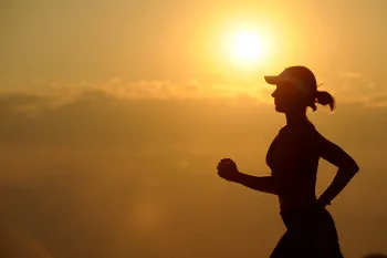 Woman running outdoors during summer heat at sunrise