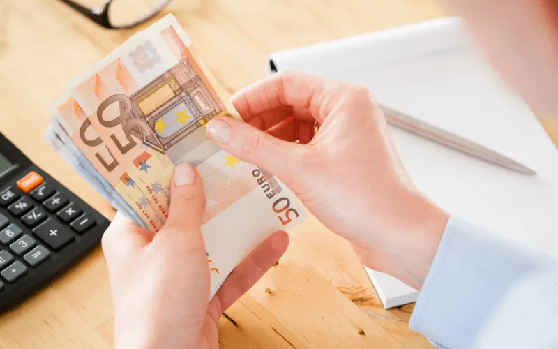 Person counting euro bills at a desk during salary budgeting in Spain