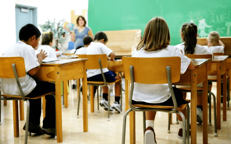 Primary school children sitting in classroom with teacher at the front