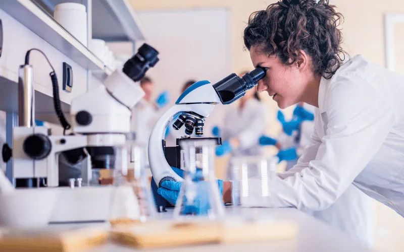 Female scientist examining samples through microscope in modern research lab