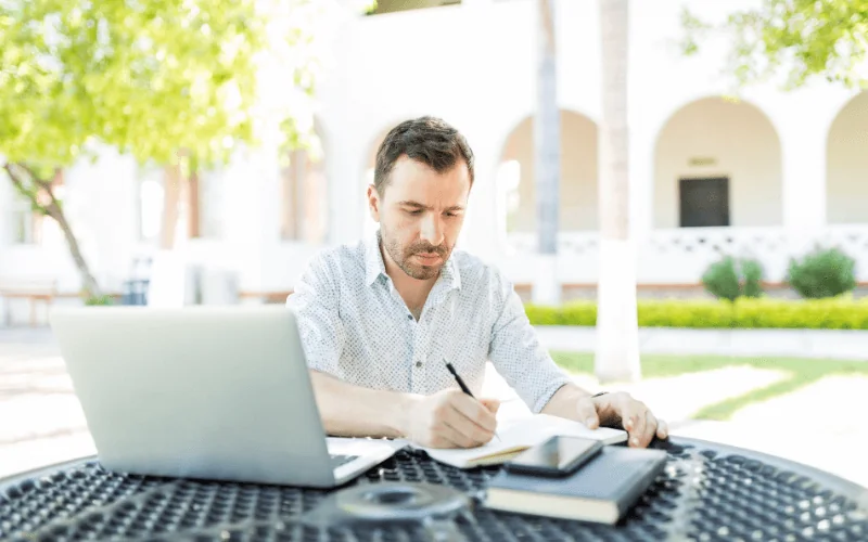 Man completing self-employed registration paperwork with laptop outdoors