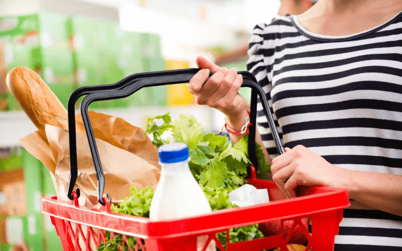 Person holding shopping basket with groceries inside a supermarket in Spain