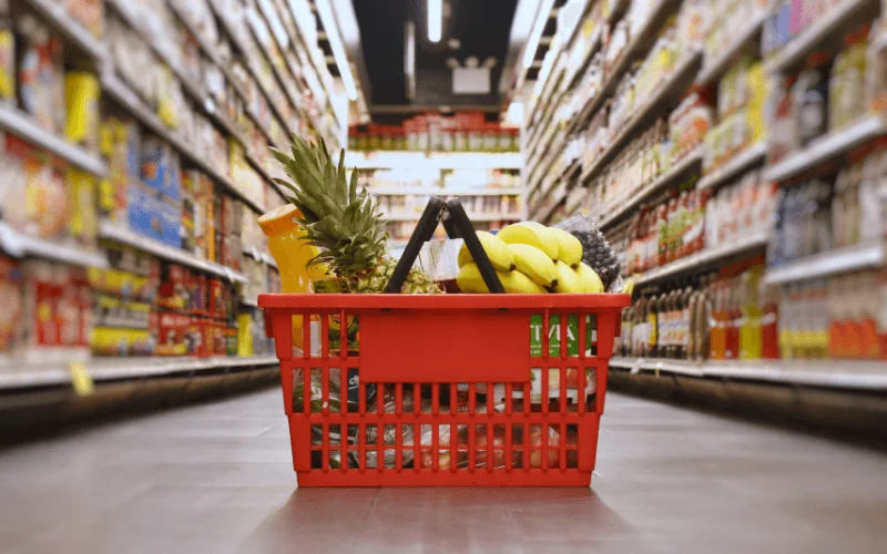 Red shopping basket filled with groceries in a Spanish supermarket aisle